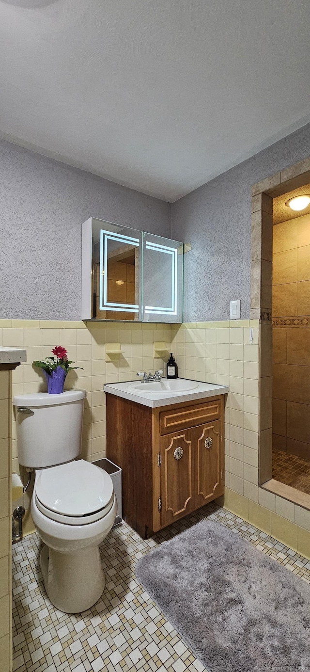258 Eddy Glover Blvd, New Britain, CT 06053 - full bathroom featuring tile walls, vanity, toilet, a wainscoted wall, and a tile shower