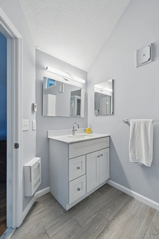 22 River Colony, Guilford, CT 06437 - bathroom featuring vaulted ceiling, vanity, a textured ceiling, wood finished floors, and heating unit