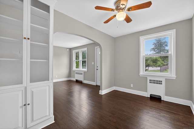 6 Crescent Dr, Danbury, CT 06810 - empty room with radiator heating unit, arched walkways, and dark wood-style floors
