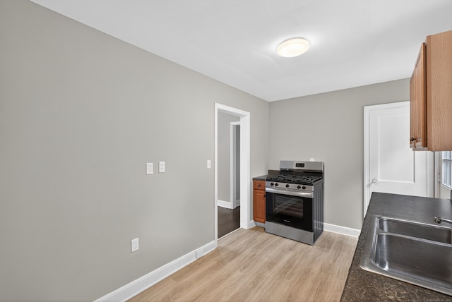 6 Crescent Dr, Danbury, CT 06810 - kitchen with stainless steel range with gas cooktop, light wood-style flooring, dark countertops, and brown cabinetry
