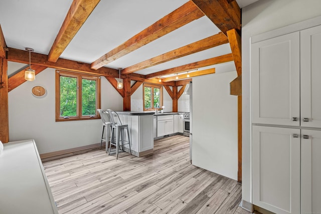 122 Old Post Rd, Old Saybrook, CT 06475 - kitchen with a peninsula, light wood finished floors, a kitchen bar, beamed ceiling, and dark countertops