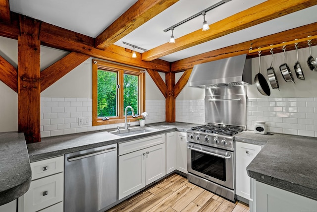 122 Old Post Rd, Old Saybrook, CT 06475 - kitchen with stainless steel appliances, wall chimney exhaust hood, dark countertops, light wood-style flooring, and backsplash