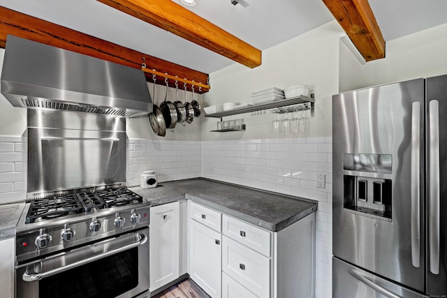 122 Old Post Rd, Old Saybrook, CT 06475 - kitchen with appliances with stainless steel finishes, wall chimney range hood, beam ceiling, dark countertops, and white cabinets