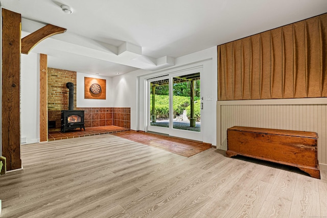 122 Old Post Rd, Old Saybrook, CT 06475 - unfurnished living room with a wood stove, wood finished floors, and wainscoting