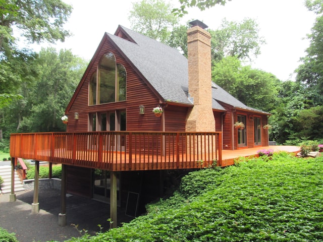 122 Old Post Rd, Old Saybrook, CT 06475 - back of property featuring roof with shingles, a deck, a chimney, and a garage