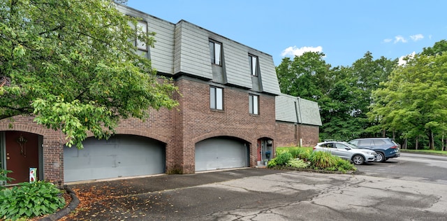70 Trolley Crossing Ln Unit 70, Middletown, CT 06457 - view of front of home featuring brick siding, mansard roof, an attached garage, and asphalt driveway