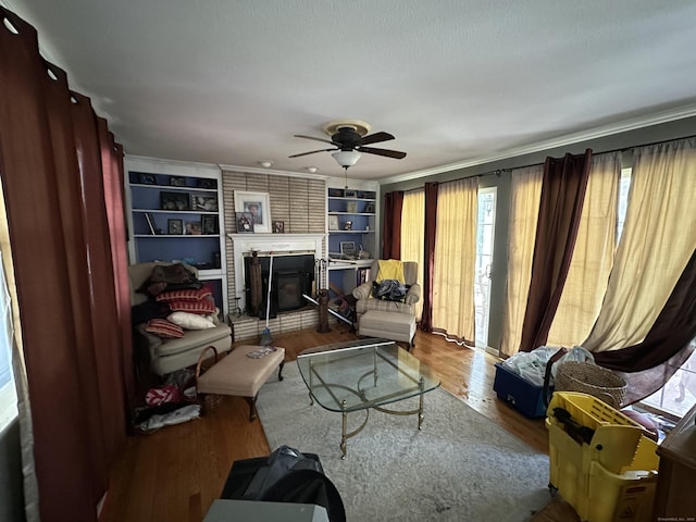 55 Kenwood Cir, Bloomfield, CT 06002 - living room with a ceiling fan, built in features, wood finished floors, a brick fireplace, and crown molding