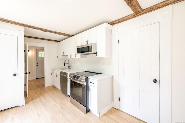 219 Redding Rd, Redding, CT 06896 - kitchen featuring appliances with stainless steel finishes, light wood-style flooring, beamed ceiling, light countertops, and white cabinets