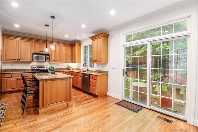 22 Woods Way Unit 22, Redding, CT 06896 - kitchen with stainless steel appliances, ornamental molding, light stone counters, a center island, and light wood-style flooring