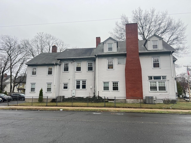670 Clinton Ave, Bridgeport, CT 06605 - view of side of home featuring a chimney, a fenced front yard, and cooling unit
