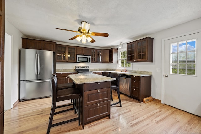 1 Brook Hill Rd, Hamden, CT 06514 - kitchen featuring stainless steel appliances, a breakfast bar, dark brown cabinetry, light wood-style flooring, and a ceiling fan