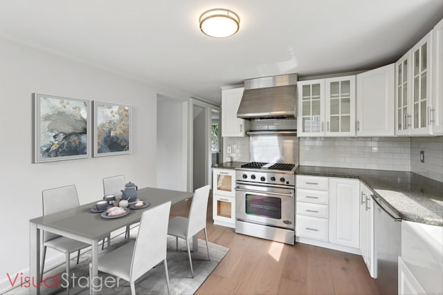 37 Cedar Crest Pl, Norwalk, CT 06854 - kitchen featuring wall chimney range hood, high end stove, wood finished floors, tasteful backsplash, and white cabinets