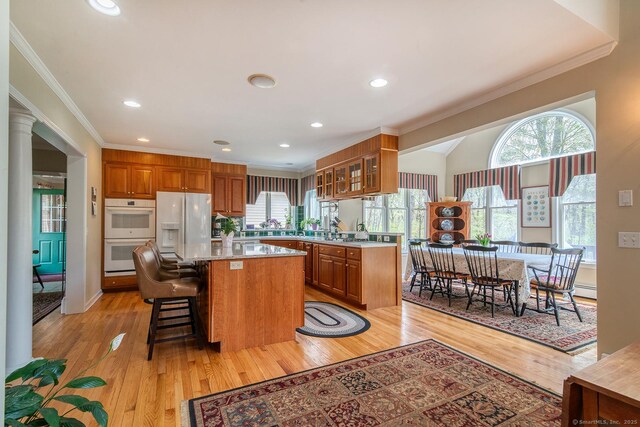 38 Fenner Ln, Stonington, CT 06378 - kitchen with white appliances, ornamental molding, brown cabinetry, glass insert cabinets, and a center island