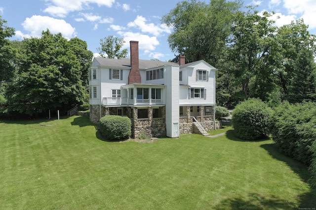 563 Main St, Ridgefield, CT 06877 - back of property with stone siding, a chimney, a porch, and a yard