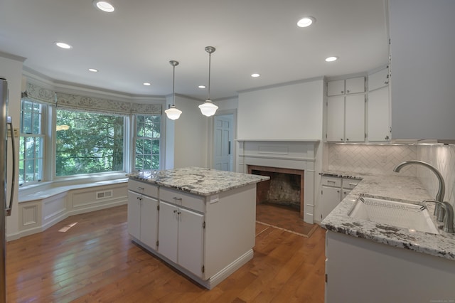 563 Main St, Ridgefield, CT 06877 - kitchen with a sink, a kitchen island, wood finished floors, decorative backsplash, and ornamental molding