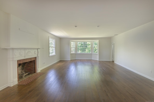 563 Main St, Ridgefield, CT 06877 - unfurnished living room featuring dark wood-type flooring, a brick fireplace, and baseboards