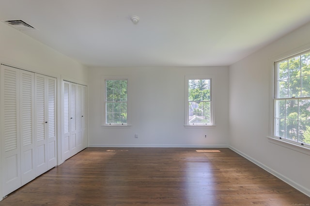563 Main St, Ridgefield, CT 06877 - unfurnished bedroom featuring multiple windows, two closets, dark wood-style flooring, and baseboards