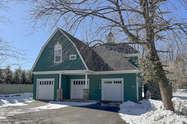 563 Main St, Ridgefield, CT 06877 - snow covered property featuring a garage and roof with shingles