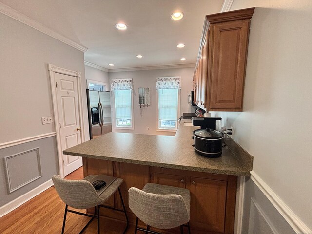 401 Cambridge Commons Unit 401, Middletown, CT 06457 - kitchen featuring stainless steel fridge with ice dispenser, a peninsula, crown molding, brown cabinetry, and a breakfast bar