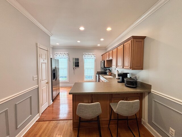 401 Cambridge Commons Unit 401, Middletown, CT 06457 - kitchen with appliances with stainless steel finishes, ornamental molding, a breakfast bar area, wainscoting, and a peninsula