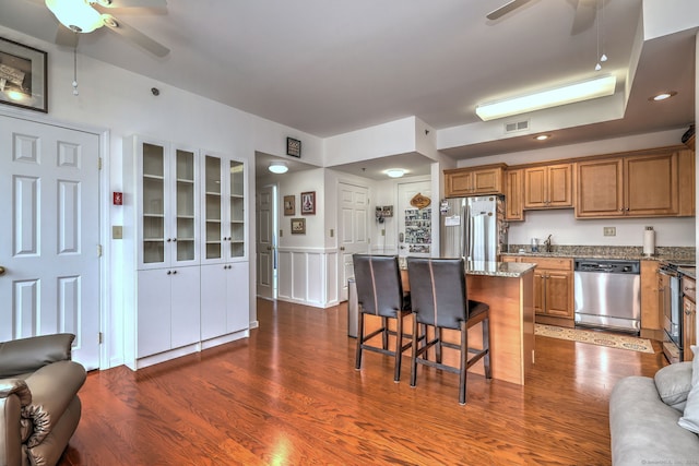 510 First Ave Unit 306, West Haven, CT 06516 - kitchen with a ceiling fan, appliances with stainless steel finishes, brown cabinetry, a breakfast bar, and a wainscoted wall