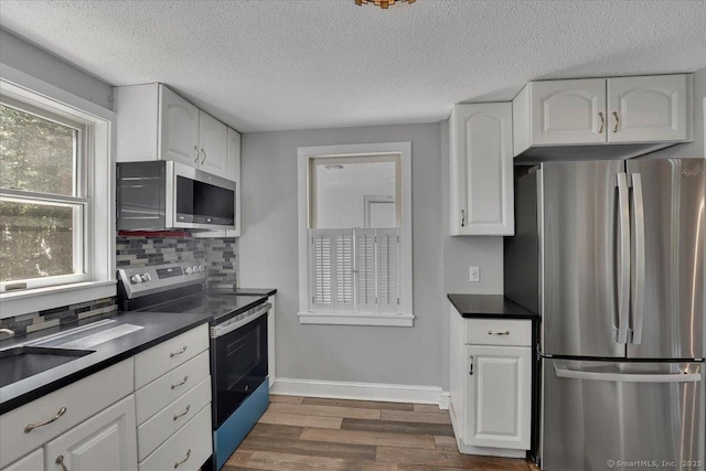 57 Whitney Rd, Columbia, CT 06237 - kitchen with stainless steel appliances, dark countertops, dark wood-type flooring, decorative backsplash, and white cabinetry