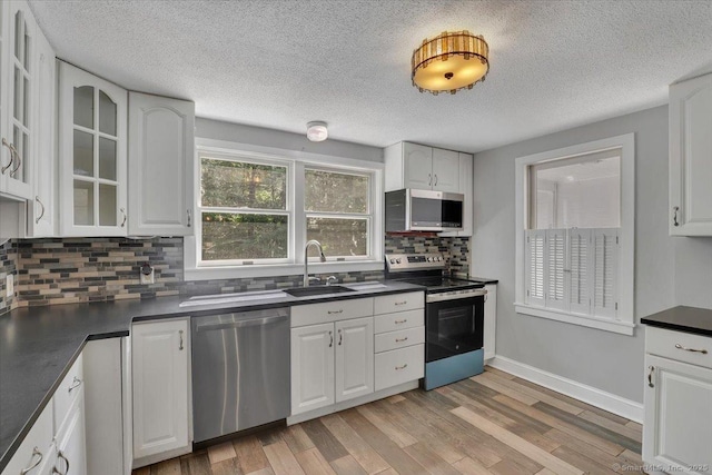 57 Whitney Rd, Columbia, CT 06237 - kitchen with stainless steel appliances, dark countertops, light wood-type flooring, backsplash, and a textured ceiling