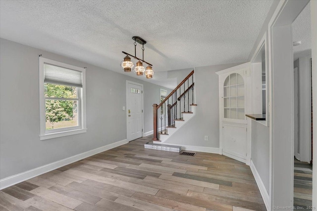 57 Whitney Rd, Columbia, CT 06237 - entrance foyer with light wood-type flooring, stairs, a textured ceiling, and a chandelier