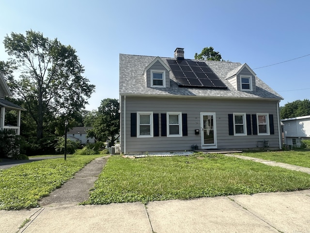 82 Trowbridge Pl, Naugatuck, CT 06770 - new england style home with roof mounted solar panels, a front lawn, a chimney, and roof with shingles