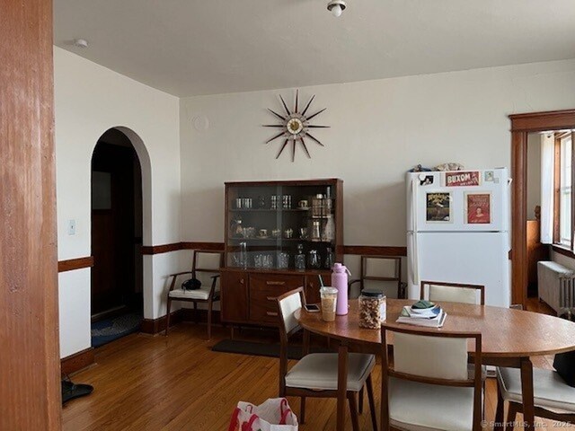 1085 Hamilton Ave, Waterbury, CT 06706 - dining area featuring wood finished floors, arched walkways, and radiator heating unit