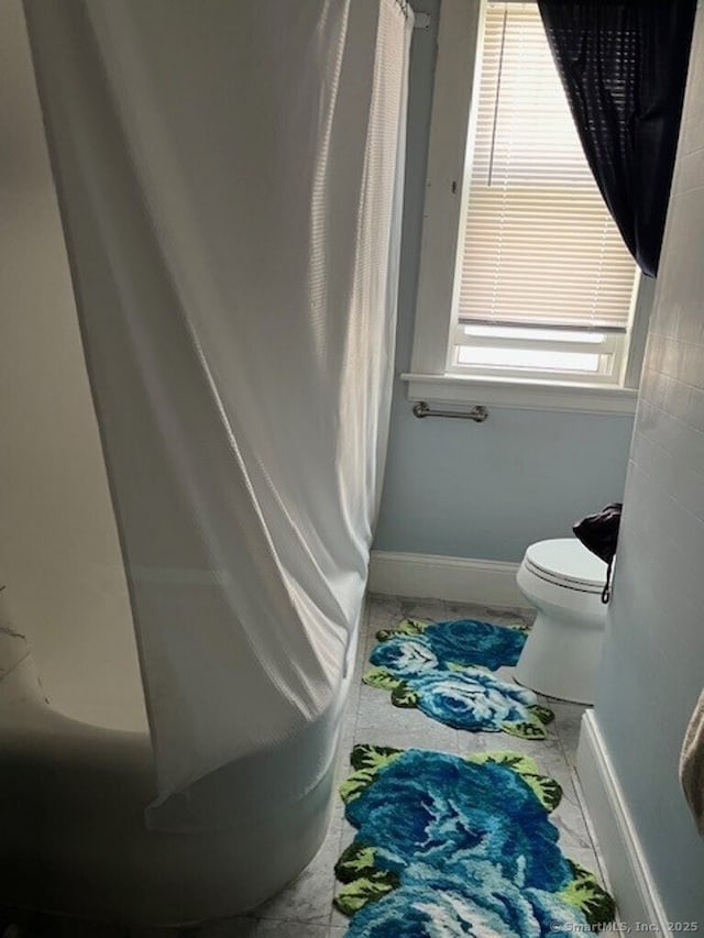 1085 Hamilton Ave, Waterbury, CT 06706 - bathroom featuring marble look tile flooring, toilet, baseboards, and a shower with shower curtain