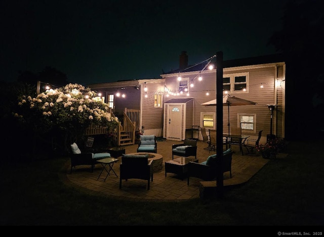20 Celestial Ln, Wallingford, CT 06492 - back of house at night with outdoor lounge area, a patio area, a chimney, and stairs