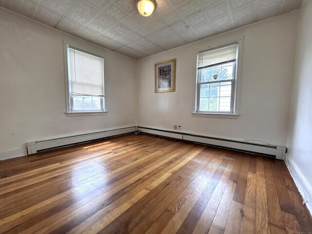 365 Ruth St, Bridgeport, CT 06606 - empty room with healthy amount of natural light, hardwood / wood-style floors, a baseboard heating unit, and an ornate ceiling