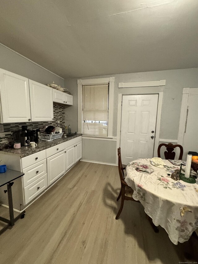 203 S Leonard St, Waterbury, CT 06708 - kitchen featuring light wood-style flooring, white cabinetry, decorative backsplash, dark countertops, and baseboards