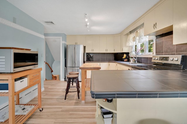 133 Savage Hill Rd, Berlin, CT 06037 - kitchen with stainless steel appliances, tile countertops, cream cabinets, and backsplash