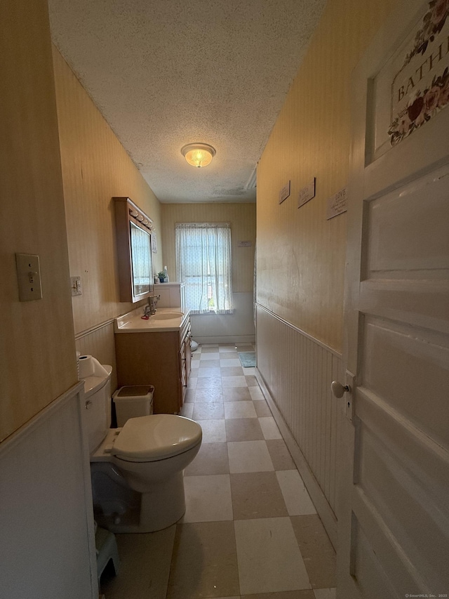 384 Park St, Bristol, CT 06010 - bathroom with tile patterned floors, vanity, a textured ceiling, and a wainscoted wall