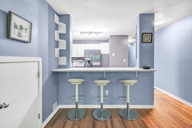 15 Perry Ave Unit D1, Norwalk, CT 06850 - kitchen with stainless steel fridge, white cabinets, a breakfast bar area, and wood finished floors