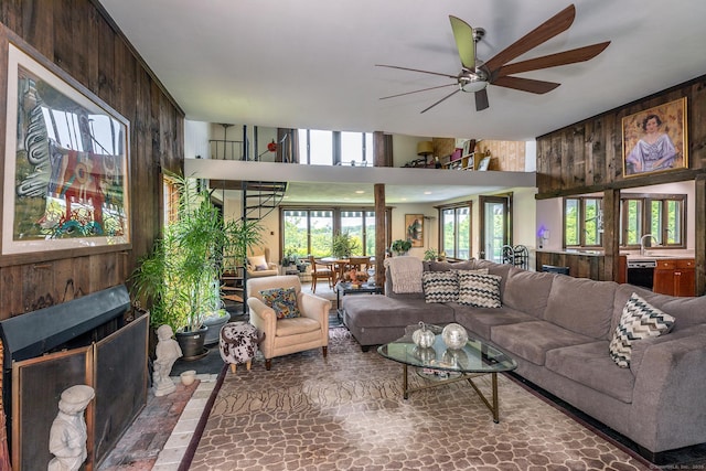 living area with a ceiling fan and wooden walls
