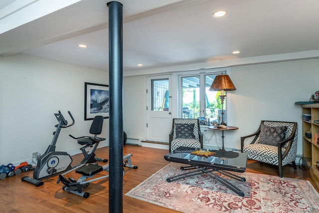 exercise area featuring wood finished floors, recessed lighting, and a baseboard heating unit