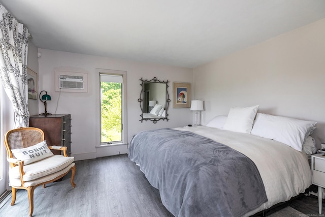 bedroom with wood finished floors and a wall mounted air conditioner