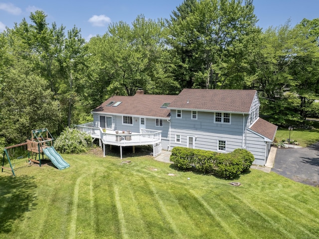 1 Blue Ridge Ln, Wilton, CT 06897 - rear view of house with a lawn, a deck, a chimney, a playground, and roof with shingles