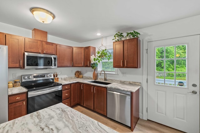 560 Laurel Hill Rd, Norwich, CT 06360 - kitchen featuring appliances with stainless steel finishes, light wood finished floors, light stone countertops, and brown cabinetry