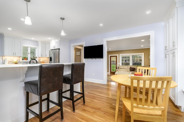 116 Knapp St, Stamford, CT 06907 - kitchen with stainless steel refrigerator with ice dispenser, white cabinetry, a breakfast bar, a peninsula, and light wood-style flooring