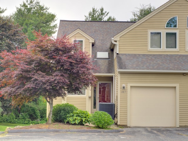 147 Courtyard Ln Unit 147, Mansfield, CT 06268 - view of front facade with central AC unit, an attached garage, a shingled roof, and driveway