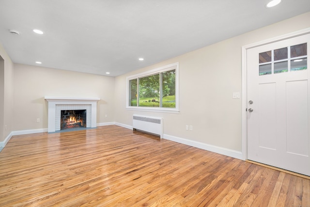 690 Bloomfield Ave, Windsor, CT 06095 - unfurnished living room featuring radiator heating unit, light wood finished floors, a brick fireplace, and recessed lighting