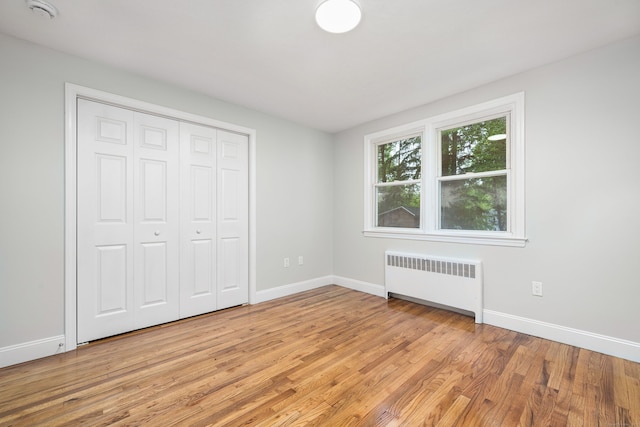 690 Bloomfield Ave, Windsor, CT 06095 - unfurnished bedroom featuring radiator heating unit, light wood-type flooring, and a closet