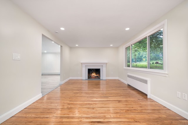 690 Bloomfield Ave, Windsor, CT 06095 - unfurnished living room with radiator heating unit, a baseboard heating unit, light wood-style floors, a brick fireplace, and recessed lighting