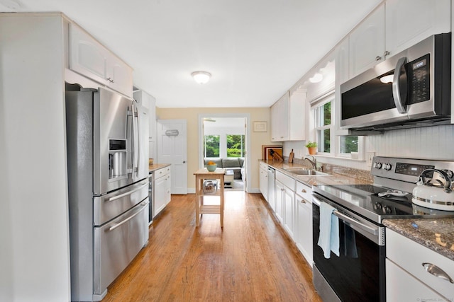 253 Gardner St, Manchester, CT 06040 - kitchen featuring appliances with stainless steel finishes, light wood finished floors, white cabinetry, and dark stone countertops