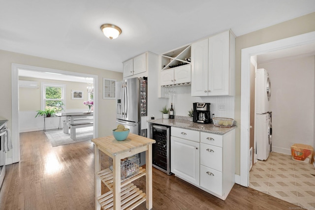 253 Gardner St, Manchester, CT 06040 - kitchen with wine cooler, stacked washer and clothes dryer, a wall unit AC, and white cabinets