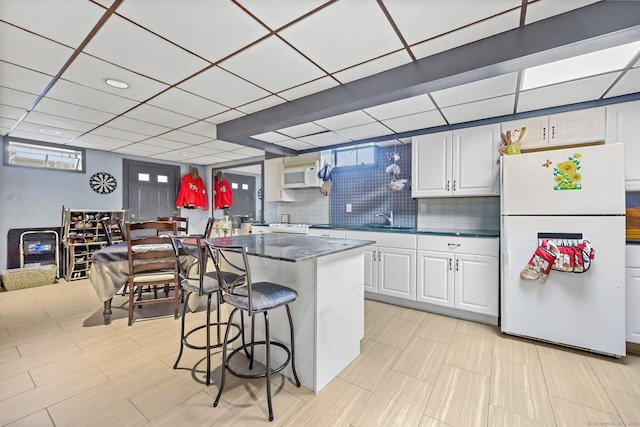 145 Arlington St, Bridgeport, CT 06606 - kitchen with white appliances, white cabinets, a breakfast bar, decorative backsplash, and dark stone counters